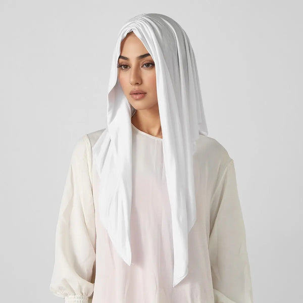 A woman wearing a white elegant triangle jersey hijab scarf and a light pink top.