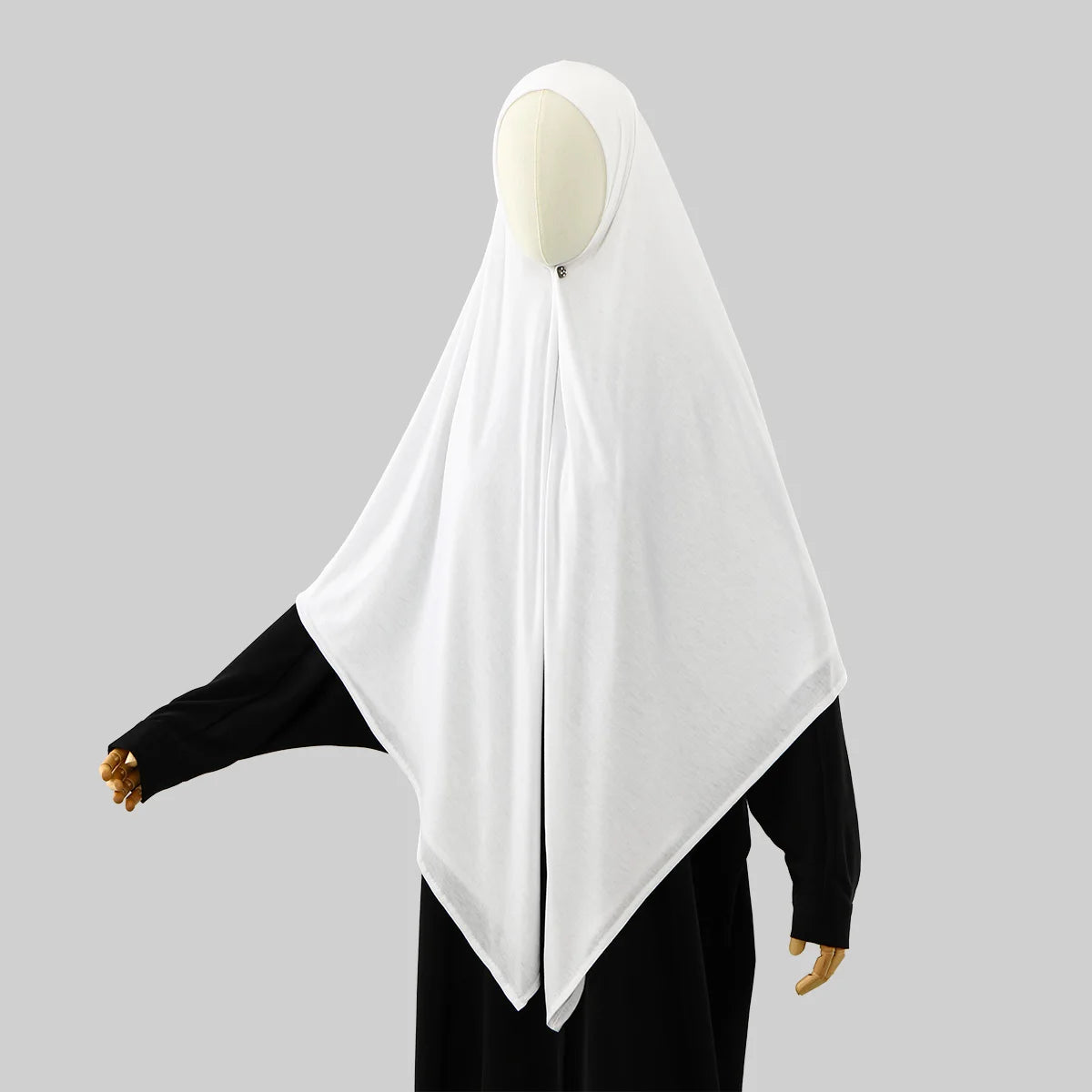 A white square scarf for Islamic wear displayed on a mannequin, paired with a black garment.