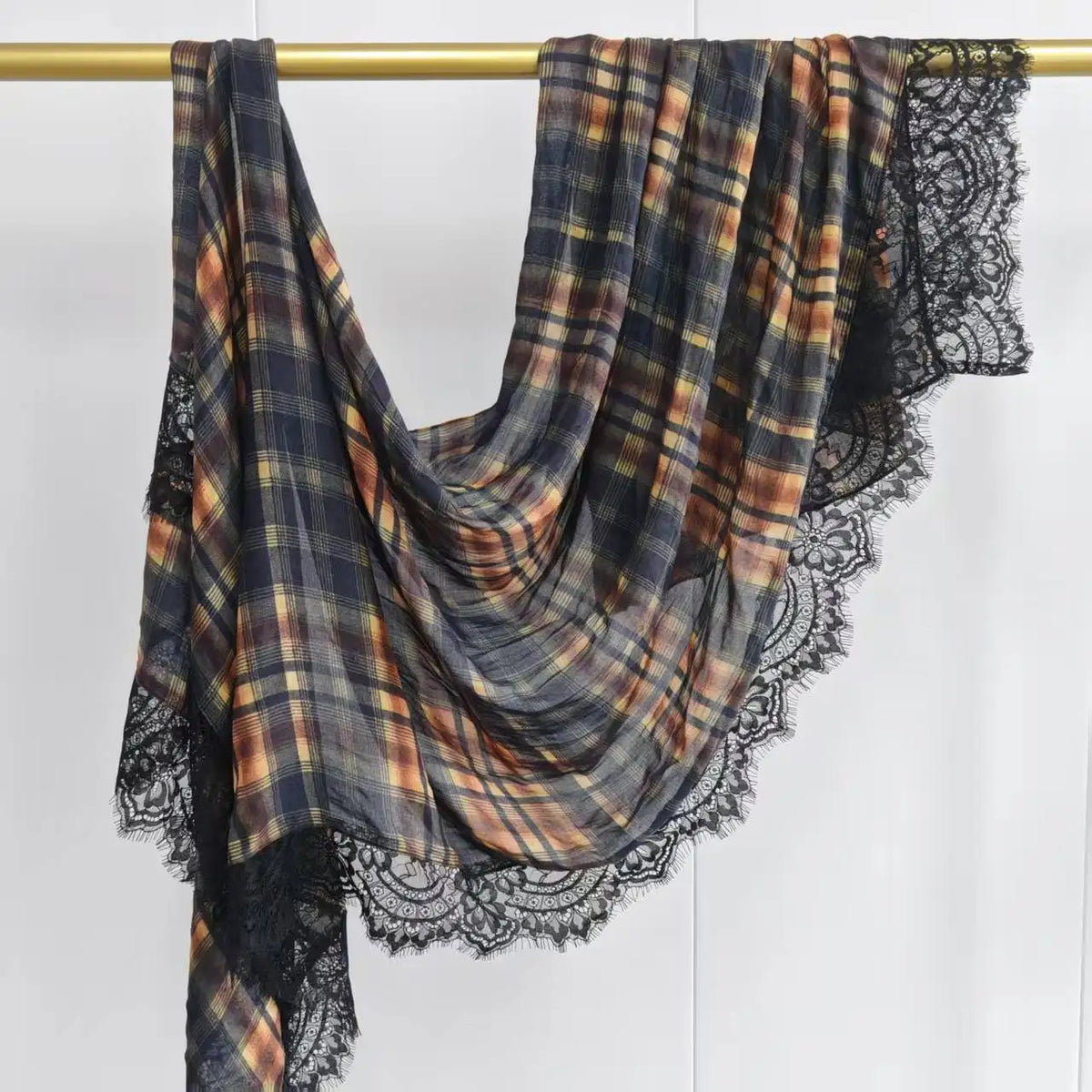 A plaid hijab scarf made of printed modal fabric in shades of brown, gray, and black, featuring lace trim.