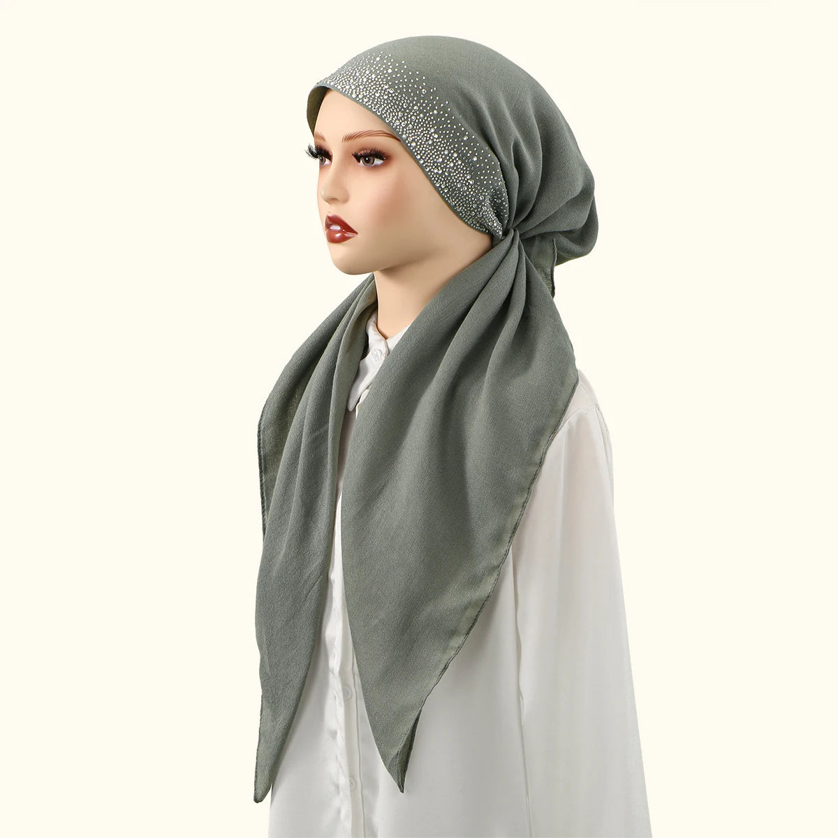 Une femme portant un bonnet hijab en lin gris uni avec des embellissements argentés et un haut blanc.