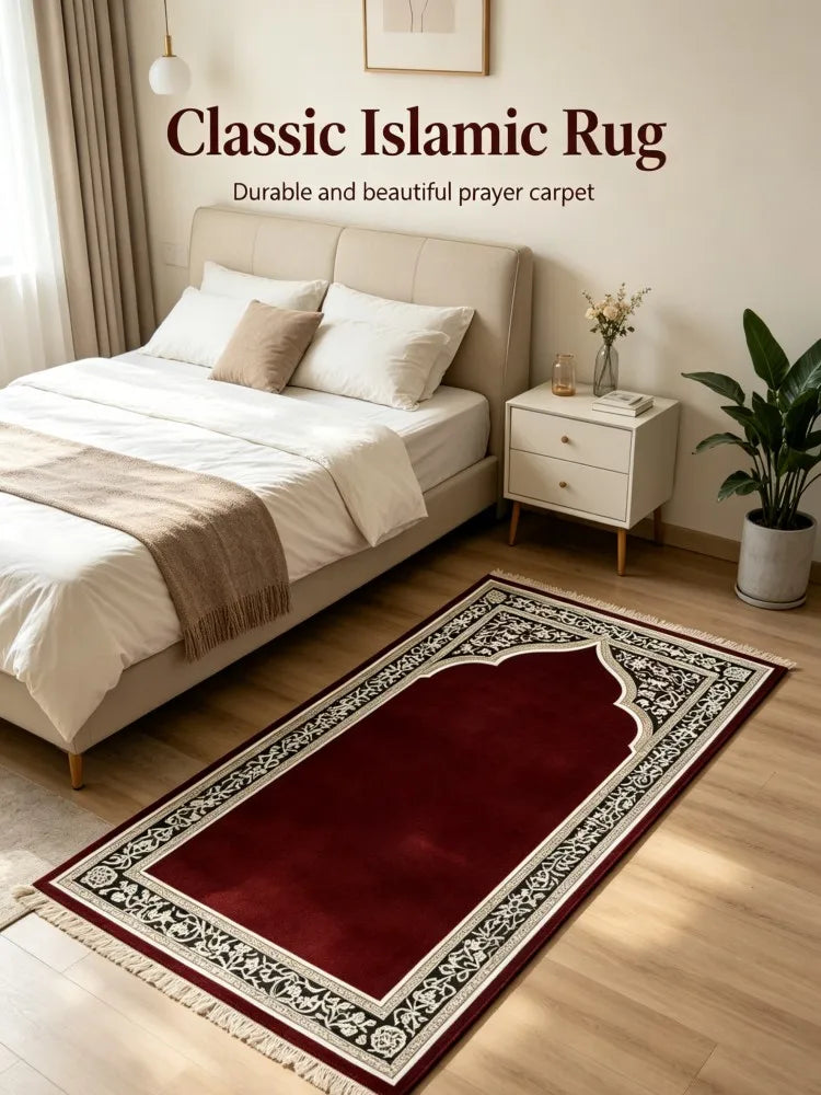Un tapis de prière islamique rouge foncé et noir exposé sur un parquet clair à côté d'un lit.