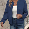 Une femme portant une veste à fermeture éclair bleu marine sur un haut blanc et un jean bleu.