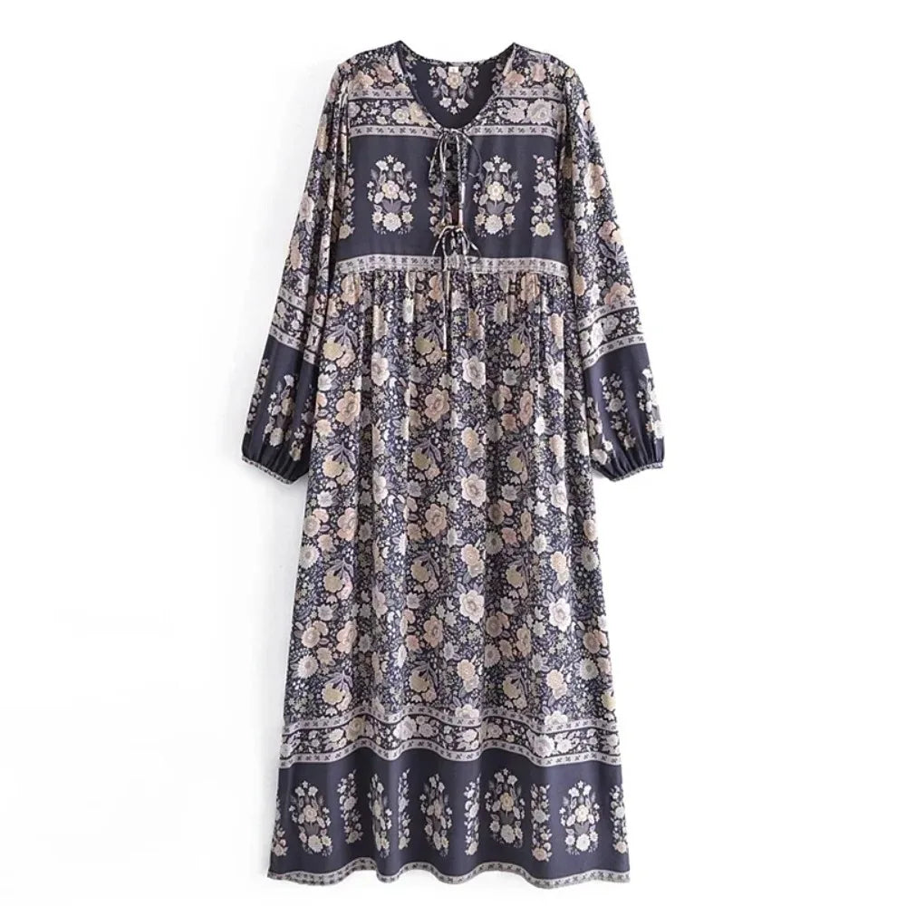 A long bohemian floral maxi dress in navy blue with intricate gold and cream patterns and lantern sleeves.
