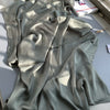 Drapierte olivgrüne Crinkle-Satin-Chiffon-Hijab-Stoff auf grauem Untergrund.