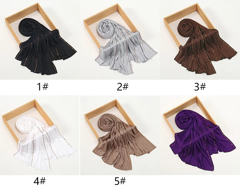 Cinco variaciones de bufandas de jersey de algodón con brillo y borde, mostradas en marcos de madera.