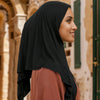 Eine Frau mit einem schwarzen Instant-Hijab-Schal über einem rostfarbenen Oberteil, im Profil gezeigt.