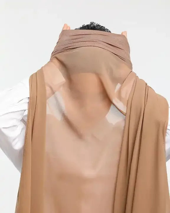 Gros plan d'un hijab en mousseline beige drapé sur la tête et les épaules d'une femme.