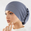 Nahaufnahme einer Frau mit einem einfarbigen blauen Stretch-Turbanmütze.