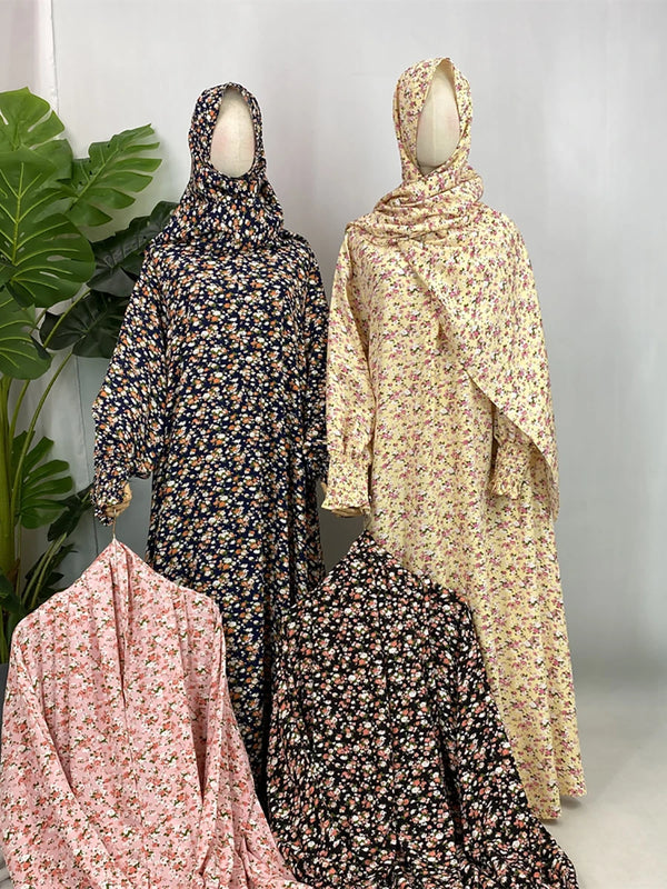 A display of three elegant floral abaya kaftans in dark blue, beige, and pink tones.