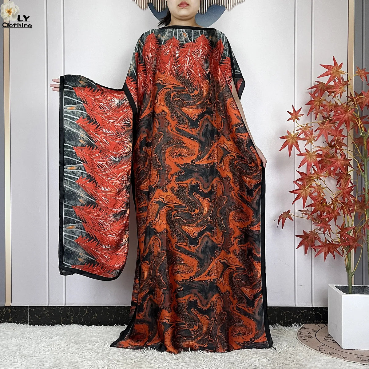 Eine Frau trägt ein fließendes orange-schwarzes abstraktes Kaftankleid