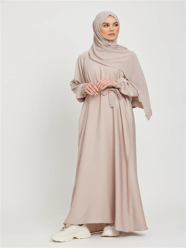 Eine Frau trägt ein beiges marokkanisches Kaftan-Abaya mit passender Hijab und weißen Schuhen.