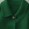 Gros plan d'un manteau en laine vert émeraude foncé à col et deux boutons visibles.