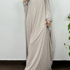 Una mujer vistiendo una elegante y fluida abaya beige clara con capucha para el Ramadán.