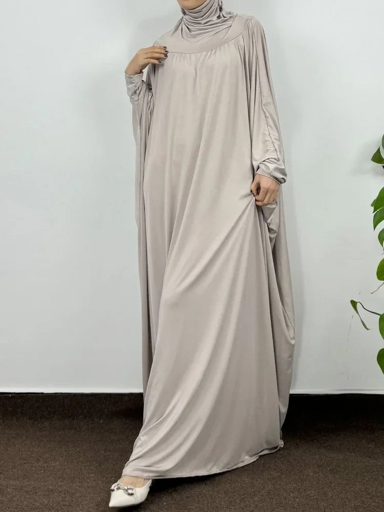 Una mujer vistiendo una elegante y fluida abaya beige clara con capucha para el Ramadán.