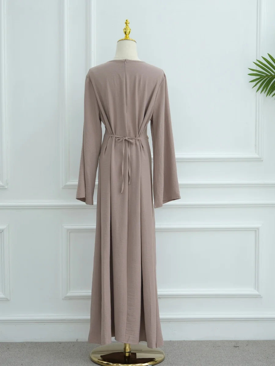 Abaya beige élégante, longue, avec cordon de serrage, présentée sur un mannequin.