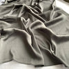 Ein Drapp von grauem gekräuseltem Satin-Chiffonstoff in einer fließenden, gefalteten Anordnung.