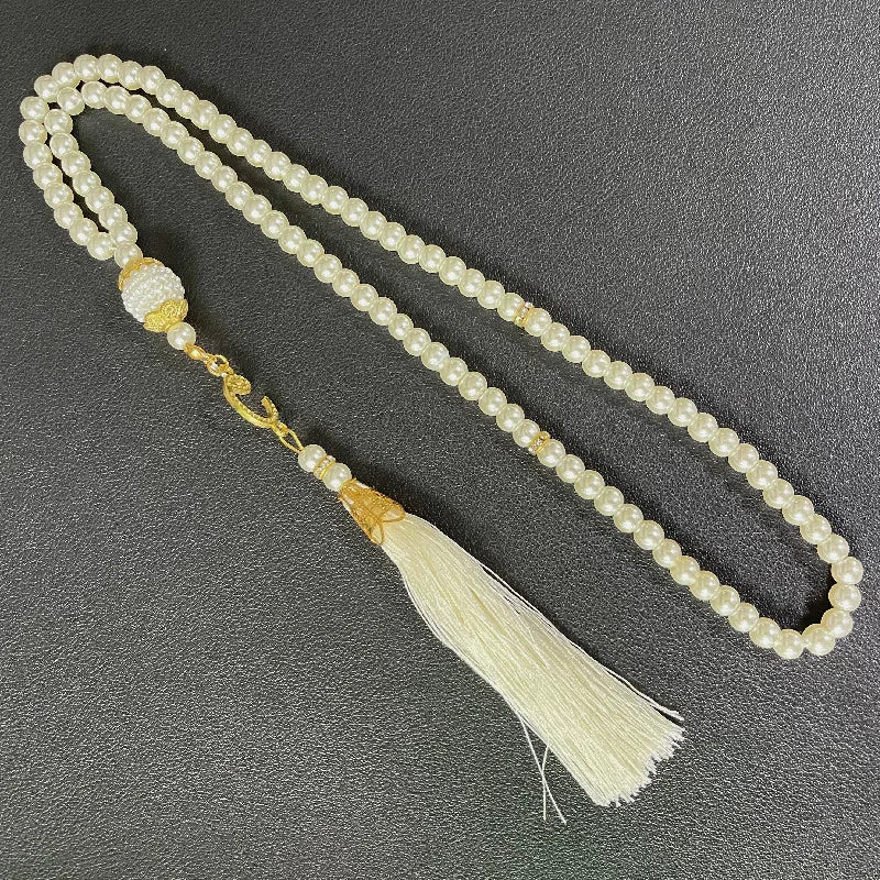 Eine Gebetsperlenarmband aus weißen Perlen mit goldenen Akzenten und einem Quaste, als islamische Gebetsrosario.