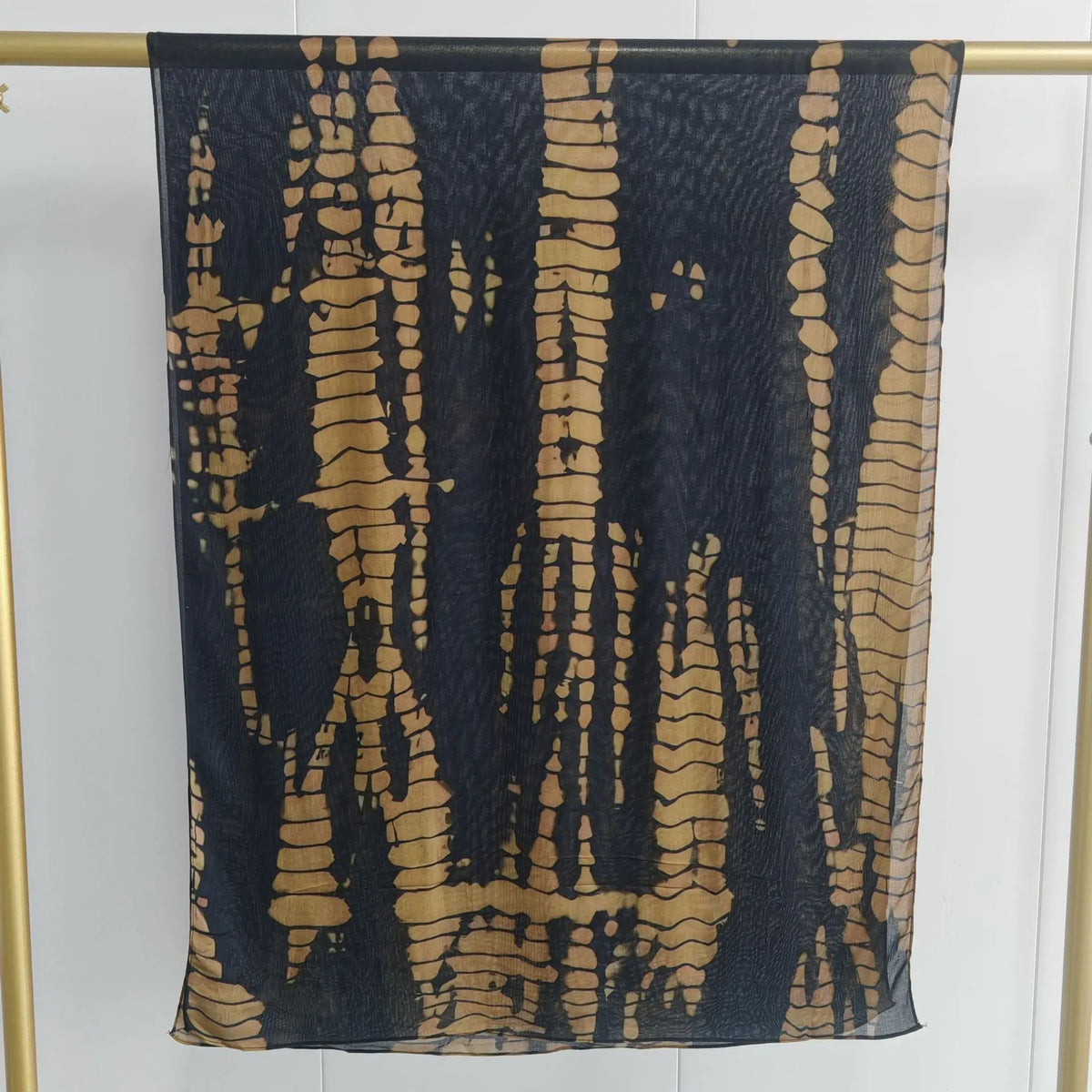 Dunkelblaue und goldene abstrakte gemusterte Schal vor hellem Hintergrund.