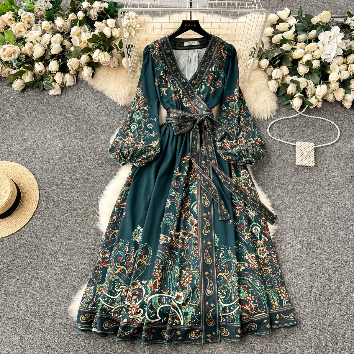 Türkisches Blumen-Spitzen-Maxikleid auf einem Bügel, umgeben von weißen Rosen und Pelz.