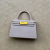 Accesorio de bolso de cuero gris claro con hebilla dorada y correa delgada.
