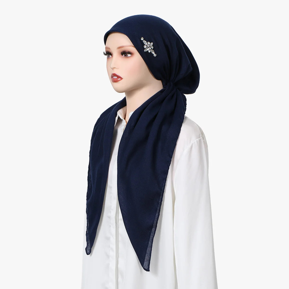 Una mujer vistiendo un gorro de hijab de lino azul marino con adornos plateados y una blusa blanca.
