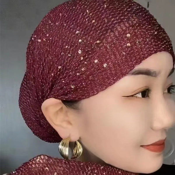 A close-up of a woman wearing an elegant, deep burgundy elastic headscarf hat adorned with sparkling rhinestones.