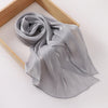 Un châle en mousseline gris argenté fluide drapé sur un cadre en bois.