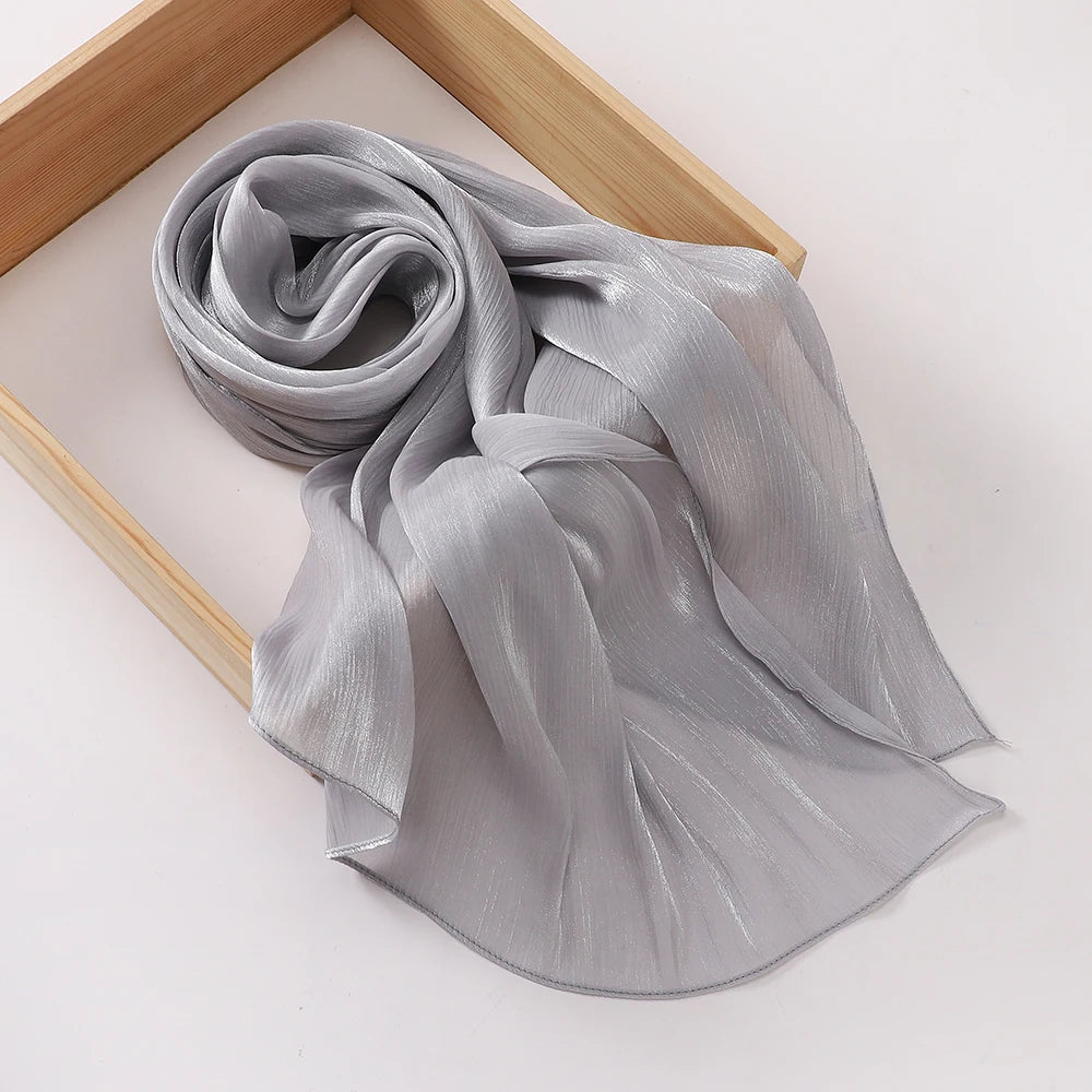 Un châle en mousseline gris argenté fluide drapé sur un cadre en bois.