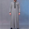 A man wearing a gray Moroccan embroidered thobe jellaba with a hood and decorative stitching.