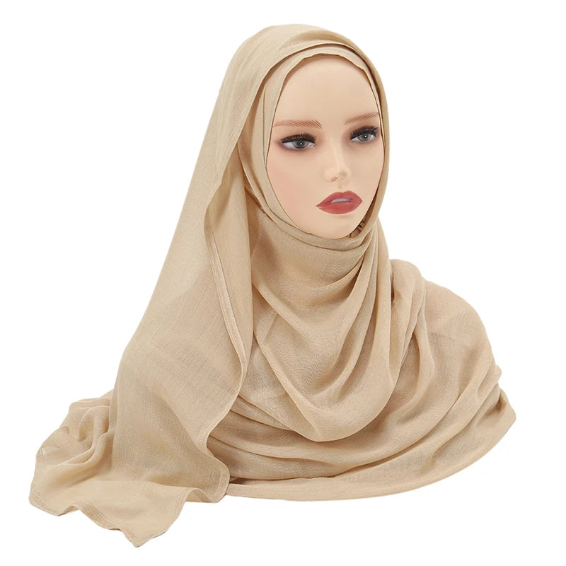Una mujer vistiendo un chal hiyab de algodón rayón beige liso, vista desde el pecho.