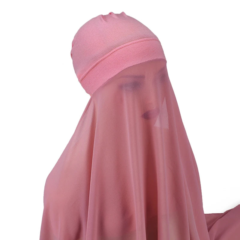 Un conjunto de hijab y chal de gasa rosa transparente drapeado sobre un maniquí.