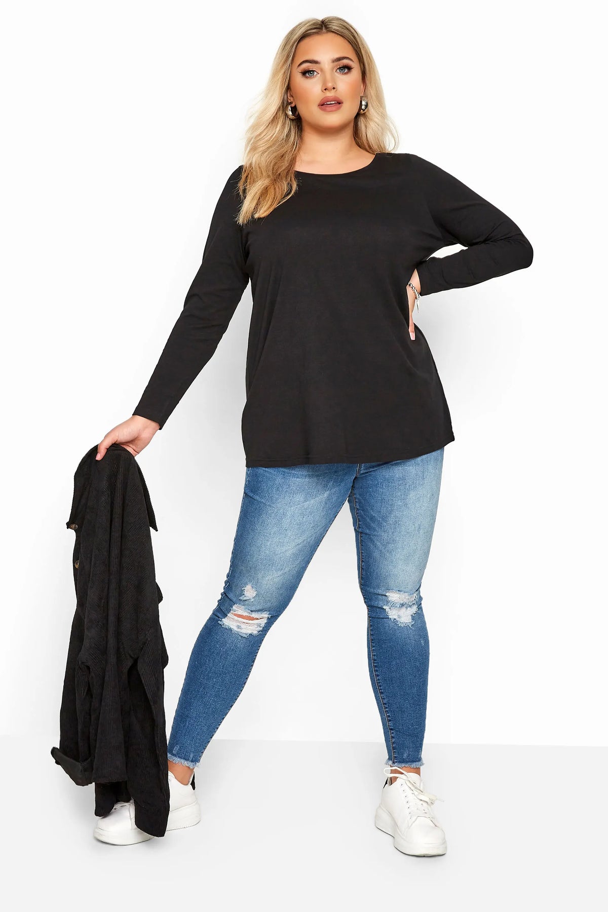 Une femme modélise un élégant t-shirt noir à manches longues en coton et un jean bleu.