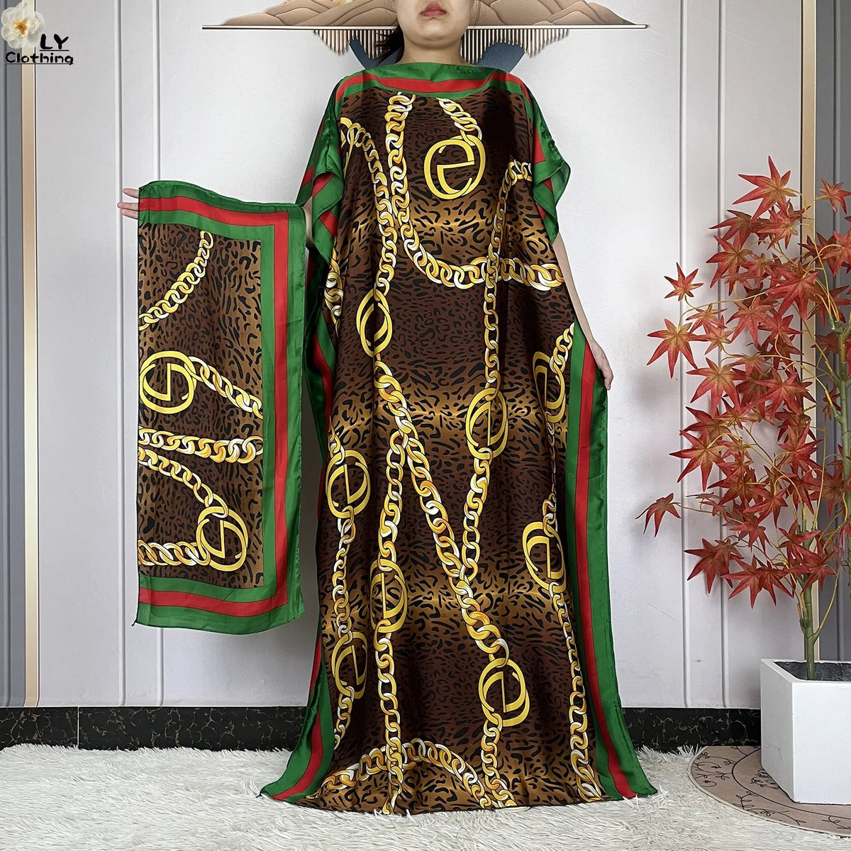 Langes braunes Leopardenmuster-Kaftan-Kleid mit goldenen Kettendetails und grünem Zierrand auf einem Mannequin.