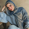 Una mujer vistiendo un pañuelo hijab de acuarela azul y gris y una blusa a juego.