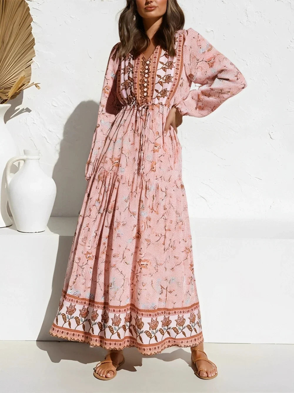 A woman wearing a pink boho floral lantern sleeve maxi dress with embroidery and tiered skirt.