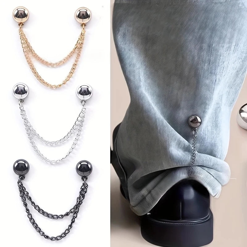 Un juego de seis clips de ropa magnéticos en cadenas doradas, plateadas y negras, mostrados contra una manga de tela gris.