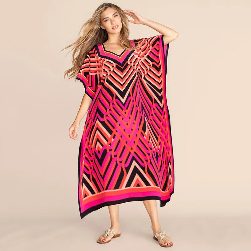 Una mujer modela un caftán de playa con estampado geométrico rosa y negro vibrante.