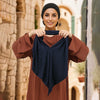 Eine Frau trägt einen dunkelblauen Instant-Hijab über einem rostfarbenen Kleid im Freien.