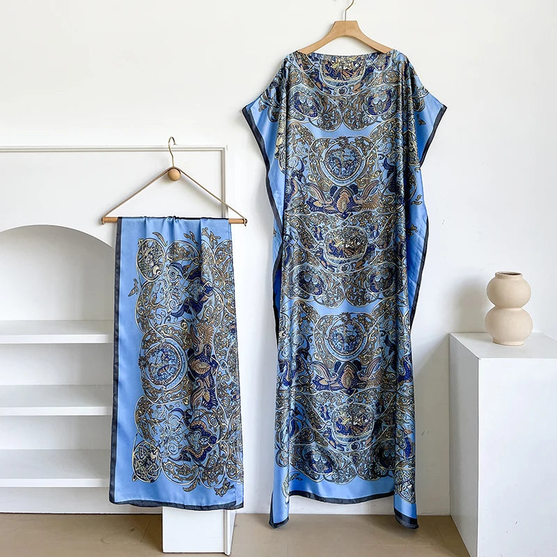 Langes, fließendes blau-goldenes Kaftankleid mit aufwendigen Paisley-Mustern an einem Holzbügel.