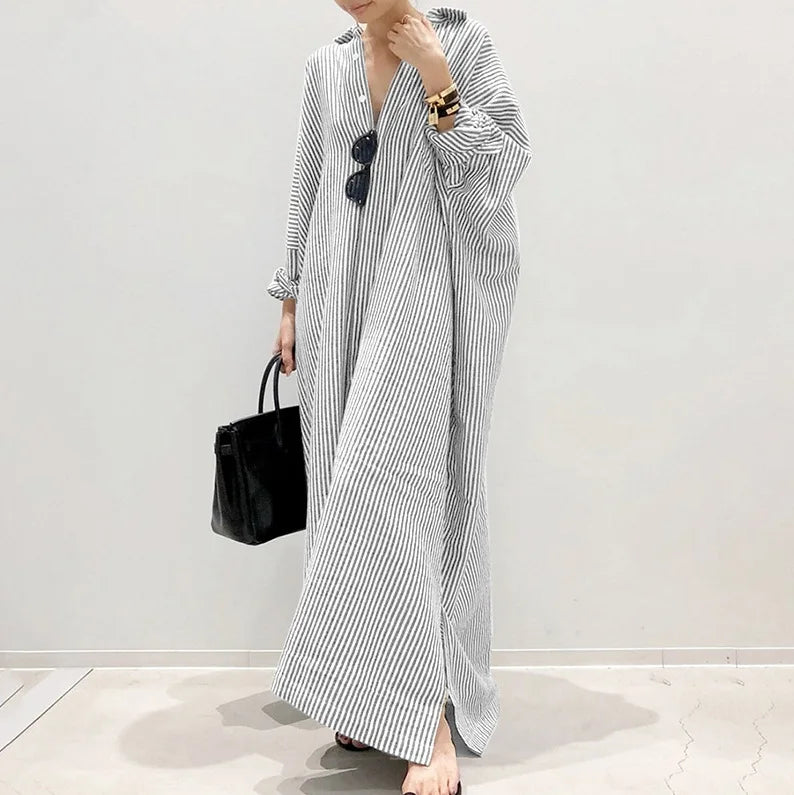 Eine Frau trägt ein langes, fließendes schwarz-weiß gestreiftes Baumwollmaxi-Kleid.