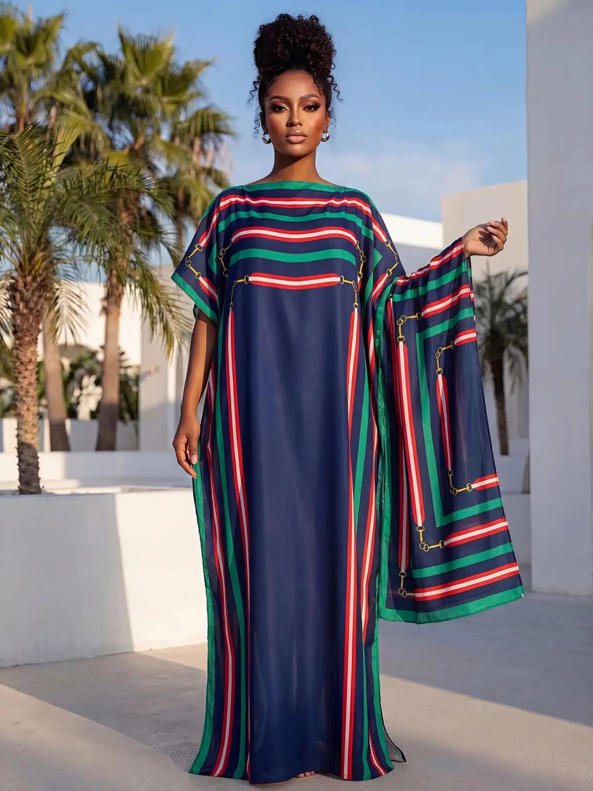 Eine Frau modelliert ein elegantes bedrucktes Seidenkaftankleid mit vertikalen Streifen in Blau, Grün und Rot vor weißem Hint