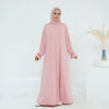 Una mujer vistiendo un vestido rosa de abaya suelto y fluido para la oración.