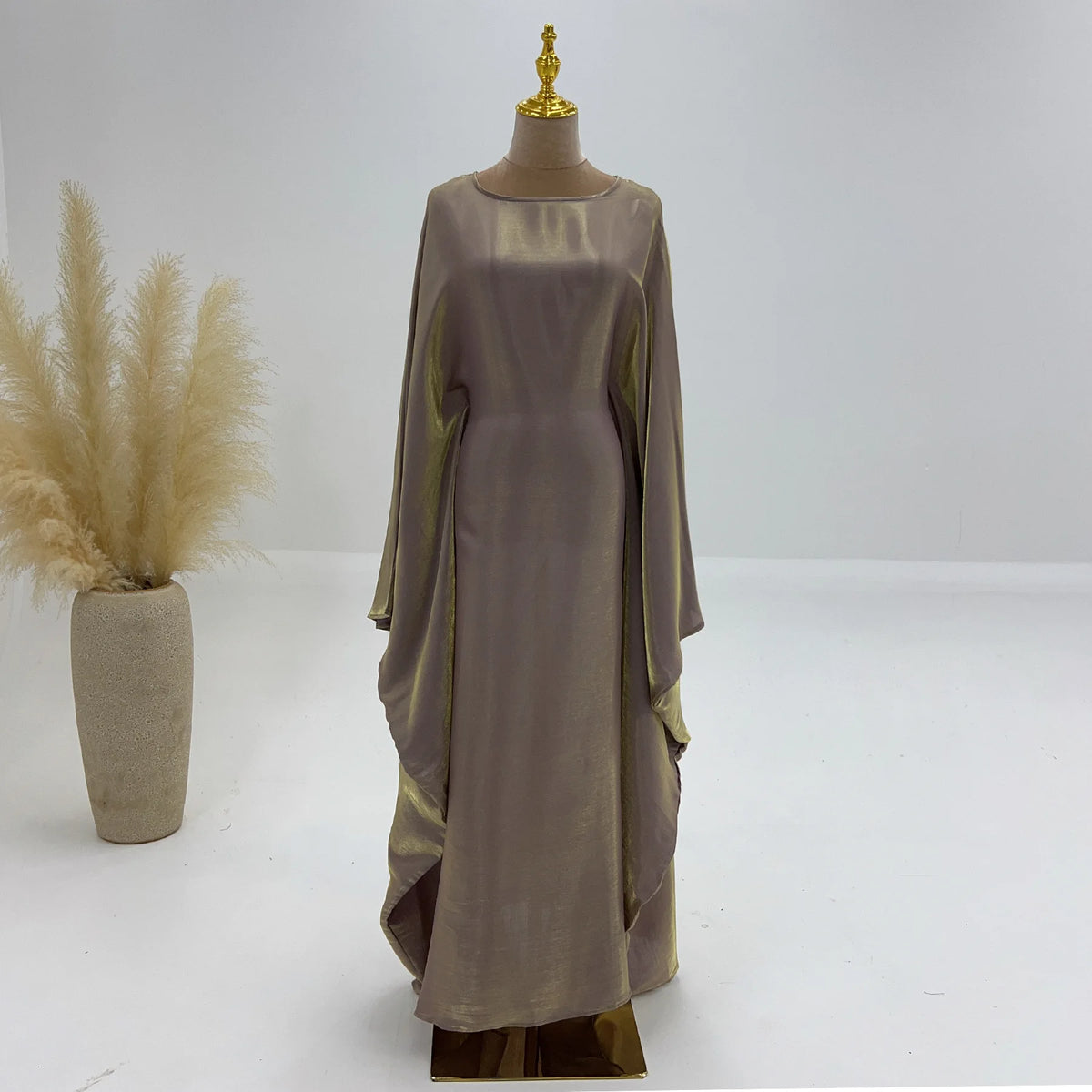 Beige, elegante, langärmelige Abaya auf einem Mannequin vor weißem Hintergrund.
