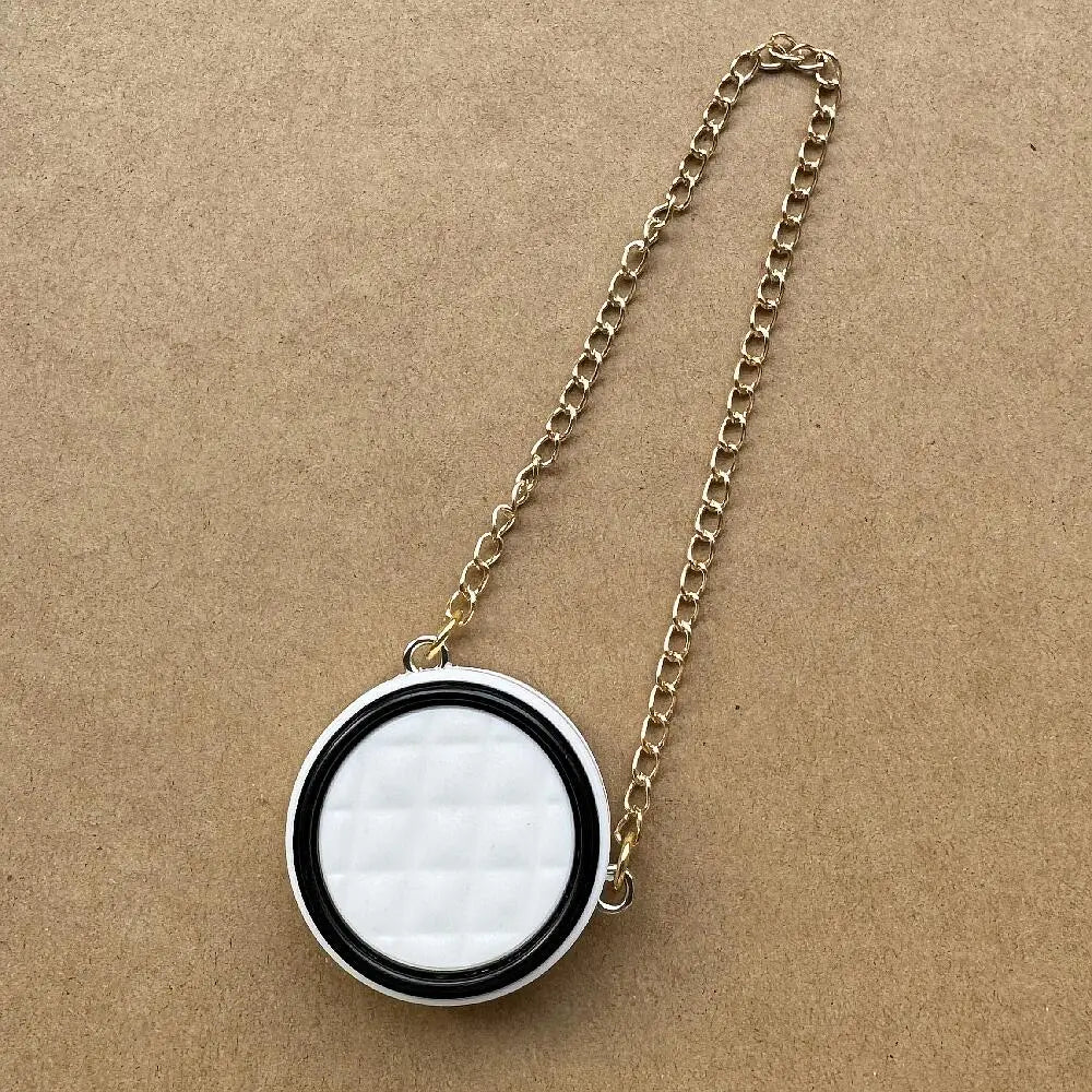 Collar de cadena de oro con colgante de patrón de diamantes blancos y negros sobre fondo marrón.