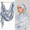 Nahaufnahme einer Frau mit einem aquarellartigen Ombré-Hijab-Schal aus Rayon-Modal in blau-weißen Blumenmustern.