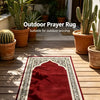 Un tapis de prière rouge profond extérieur avec calligraphie arabe blanche sur une terrasse en bois entourée de cactus en pot