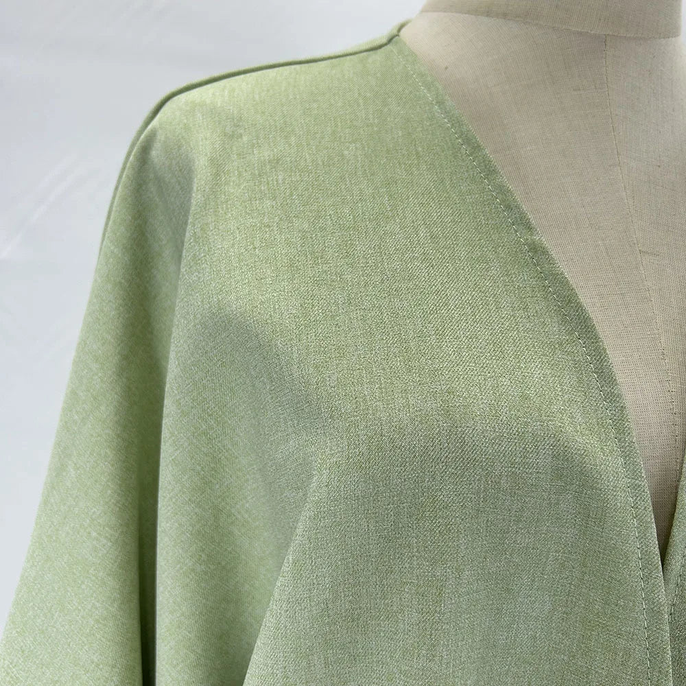 Helles salbeigrünes Leinenkimono-Abaya, drapiert auf einem Mannequin.