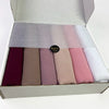 Eine Box mit einer Sechs-Packung pastellfarbener Chiffon-Hijabs in Violett-, Rosa- und Beige-Tönen.