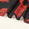 Primer plano de un pañuelo o hijab de gasa roja floral transparente con bordes festoneados.