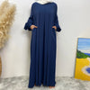 Elegantes, dunkelblaues, langes islamisches Kleid für Damen vor weißer Wand.